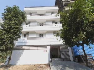 un bâtiment blanc avec des arbres devant lui dans l'établissement OYO Ooak Hotels Delta 1, à Greater Noida