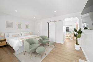 a white bedroom with green chairs and a bed at M Lake Worth Beach - Modern Apartments Near West Palm Beach in Lake Worth