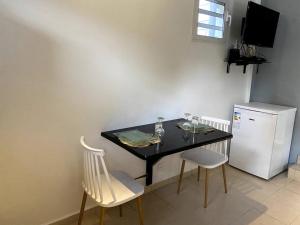 une table noire avec deux chaises et un réfrigérateur dans l'établissement On ti kanpo, à Bosrédon