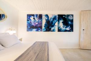 1 dormitorio con 3 pinturas en la pared en Tafat's Haven Lodge, en Nurit