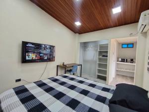 a bedroom with a bed with a tv on the wall at Hermosa suite acogedora, Las Garzas in Guayaquil