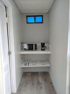 a kitchen with white shelves and a microwave at Hermosa suite acogedora, Las Garzas in Guayaquil