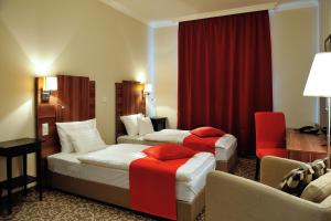 a hotel room with two beds and a red curtain at Corner Hotel & Kávéház in Dunaújváros +7 photos
