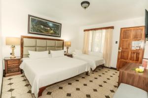 1 dormitorio con 2 camas blancas y ventana en Hotel Villabosque Eco Boutique, en Manuel Antonio