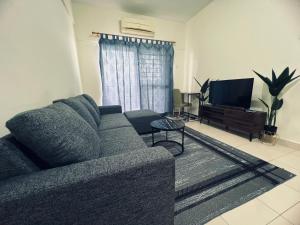 a living room with a couch and a television at JR GUESTHOUSE in Ampang