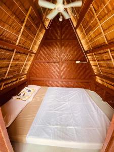 Cama en una cabaña de paja con ventilador de techo en Destiny Rainbow Beach Resort en Siquijor