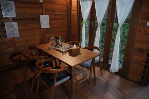 una mesa de madera y sillas en una habitación con ventana en Arkamaya Kusuma Resort en Yogyakarta