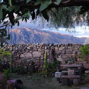 a stone wall with a bench and mountains in the background at Hostal Samary Wasi in Estancia Chaunaca
