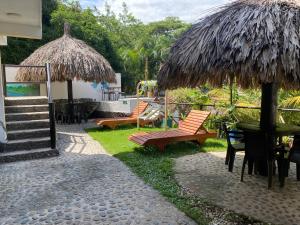 eine Terrasse mit einem Tisch, Stühlen und einem Sonnenschirm in der Unterkunft Hotel Manakin Tayrona in El Zaino