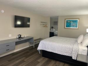 um quarto com uma cama e uma secretária com uma televisão em Economy Inn Historic District em Saint Augustine