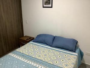 a bedroom with a bed with blue pillows and a table at Cómoda habitación con baño privado in Sabaneta