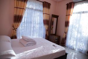a bedroom with a white bed with curtains and a mirror at WIMAL PALACE in Jaffna