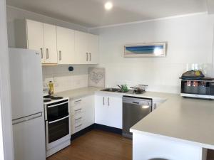 a kitchen with white cabinets and a white refrigerator at Endeavour Reach in Cooktown