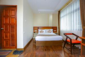 a bedroom with a bed and a chair and a window at HOTEL KEIO YANGON in Rangoon Ahlone