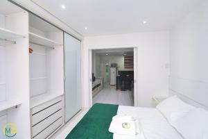 1 dormitorio con cama blanca y alfombra verde en Studio com vista lateral para o mar em Copacabana en Río de Janeiro