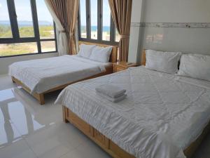 two twin beds in a room with a large window at HOTEL VTV DỐC LẾT in Ninh Hòa