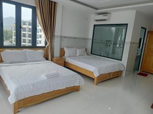 a bedroom with two beds and a large window at HOTEL VTV DỐC LẾT in Ninh Hòa +8 photos