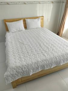 a bed with a white comforter and pillows at HOTEL VTV DỐC LẾT in Ninh Hòa