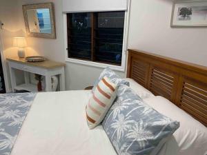 a bedroom with a bed with a window and a pillow at Sunbird Studio Apartment: private apartment walking distance from the beach in Trinity Beach