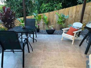 a patio with chairs and tables and a fence at Sunbird Studio Apartment: private apartment walking distance from the beach in Trinity Beach