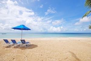 two chairs and an umbrella on a beach at Schooner Bay 112 by Blue Sky Luxury in Saint Peter