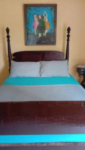 a bed with a wooden headboard and a painting on the wall at Bigin Garden View Resort 