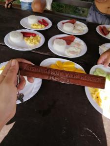 a person holding a wooden ruler with food on plates at Bigin Garden View Resort 