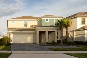 a house with a garage and a palm tree at Waterfront Brand New Modern Luxury 8 BR pool house! Sleeps 16 in Kissimmee