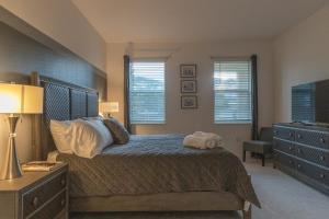 a bedroom with a bed and a dresser and windows at Waterfront Brand New Modern Luxury 8 BR pool house! Sleeps 16 in Kissimmee