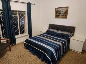 a bedroom with a bed with a blue and white striped blanket at The Rose 47 4th Street Albertskroon in Johannesburg +6 photos