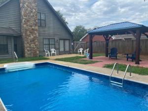 a swimming pool with a gazebo next to a house at Relaxing Oasis with Pool Gazebo in Family-Friendly Neighborhood in Montgomery