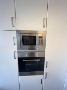 a microwave oven in a kitchen with white cabinets at La Sardineta del Serrallo in Tarragona