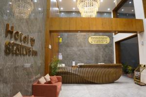 een lobby met een bruine bank en een bord aan de muur bij HOTEL STATURE INN in Kevadia