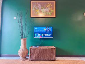 ein Wohnzimmer mit einer Vase und einem TV an der Wand in der Unterkunft The Heritage@Selesa Hillhomes Bukit Tinggi Berjaya Hills Bentong in Bentong