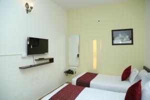 a hotel room with two beds and a tv at Hotel Bangalore Airport inn, Airport Pickup & Drop Available 24X7 in Yelahanka