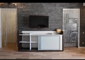 un salon avec une télévision sur un mur en briques dans l'établissement La Magnifique, à Mandelieu-la-Napoule