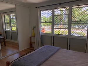 a bedroom with two large windows and a bed in it at Endeavour Reach in Cooktown