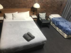 ein Hotelzimmer mit 2 Betten und einem Stuhl in der Unterkunft Golden West Motor Inn in Miles