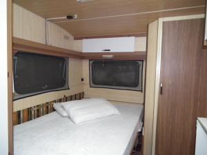 a small bed in an rv with two windows at Campeggio Ricortola Mare in Marina di Massa