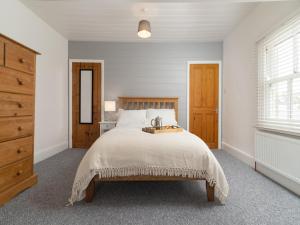 Dormitorio blanco con cama grande y cabecero de madera en Bright~ Town Center~ 2 bed~Penzance, en Penzance