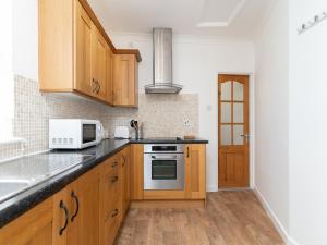a kitchen with wooden cabinets and a microwave at Bright~ Town Center~ 2 bed~Penzance in Penzance