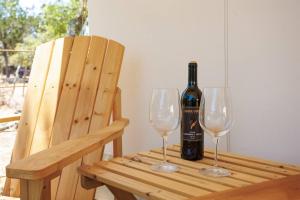 Una botella de vino sentada en una mesa de madera con dos copas en Twin Falls Luxury Glamping - Escape Tent, en Boerne