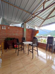 d'une terrasse avec une table, des chaises et un mur en briques. dans l'établissement Garrison Alojamiento , selva y Turismo y Comida, à Tingo María