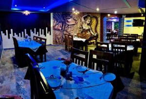 een restaurant met blauwe tafels en stoelen en een muurschildering bij Hotel Jasmin Palace in Angul