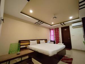 een slaapkamer met een bed, een tafel en een bureau bij Hotel Jasmin Palace in Angul