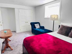 a bedroom with a red bed and a blue chair at 2 Bedrooms Private Basement Suite Close to Winsport & Downtown in Calgary
