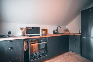 a kitchen with black cabinets and a microwave at Korter vanalinna peatänaval in Viljandi