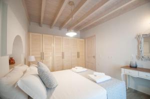 een slaapkamer met een wit bed en een houten plafond bij LUCA'S HOUSES in Halki