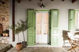 a green door with shutters and a potted plant at LUCA'S HOUSES in Halki