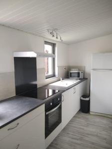 a kitchen with white counters and a white refrigerator at La Tanière des Pandas in Chabris